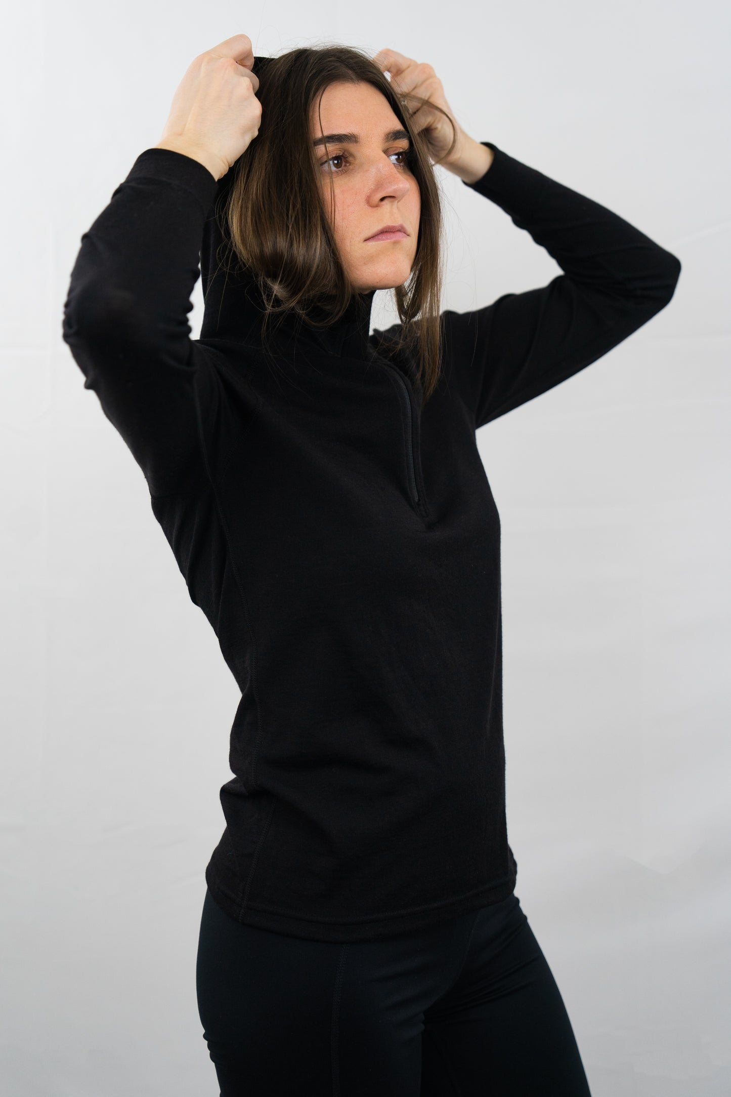 Person wearing womens black wool base layer hoodie with hood on from Squak Mountain Co.