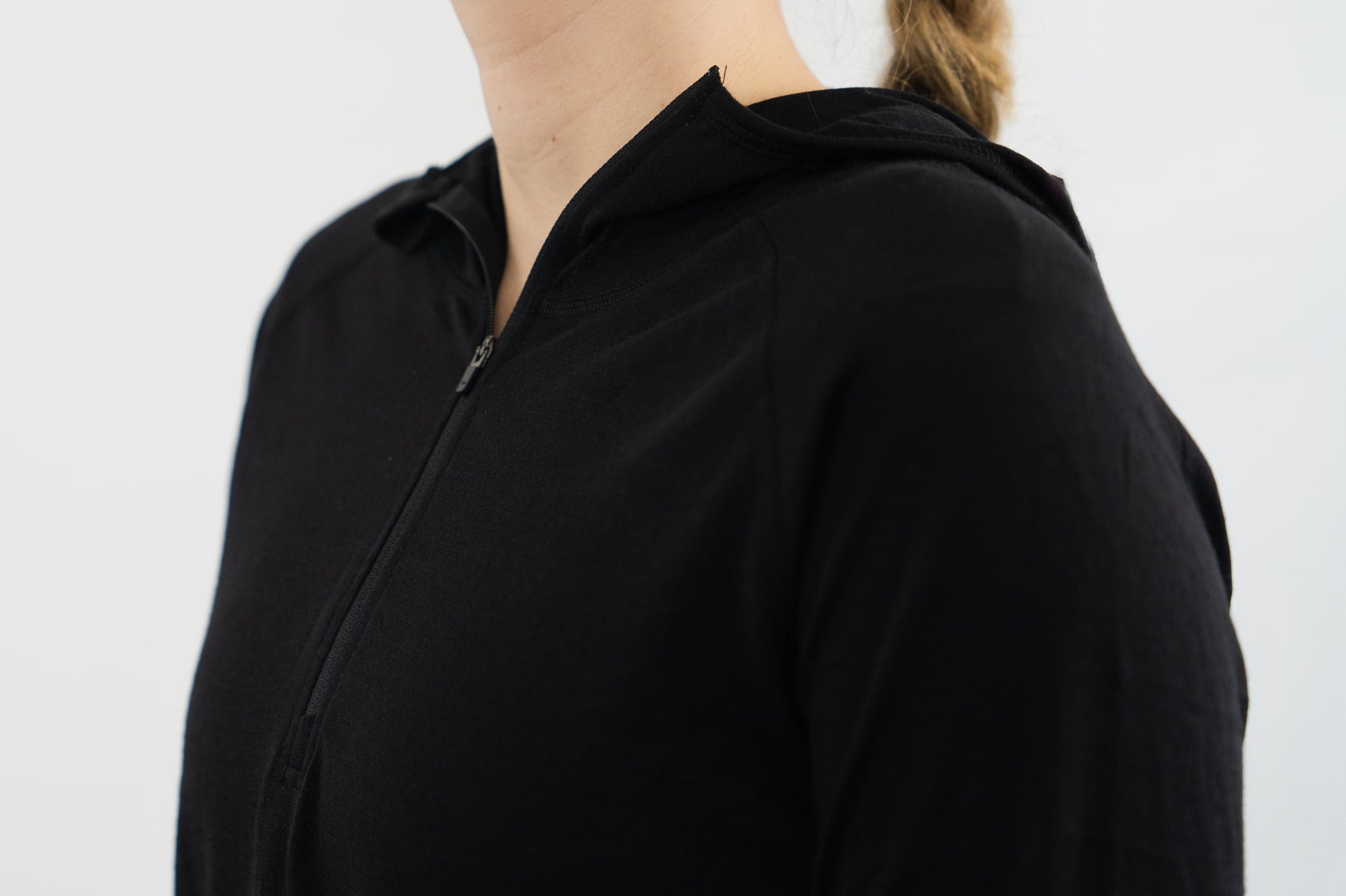 Top half of person wearing womens black wool base layer hoodie from Squak Mountain Co.