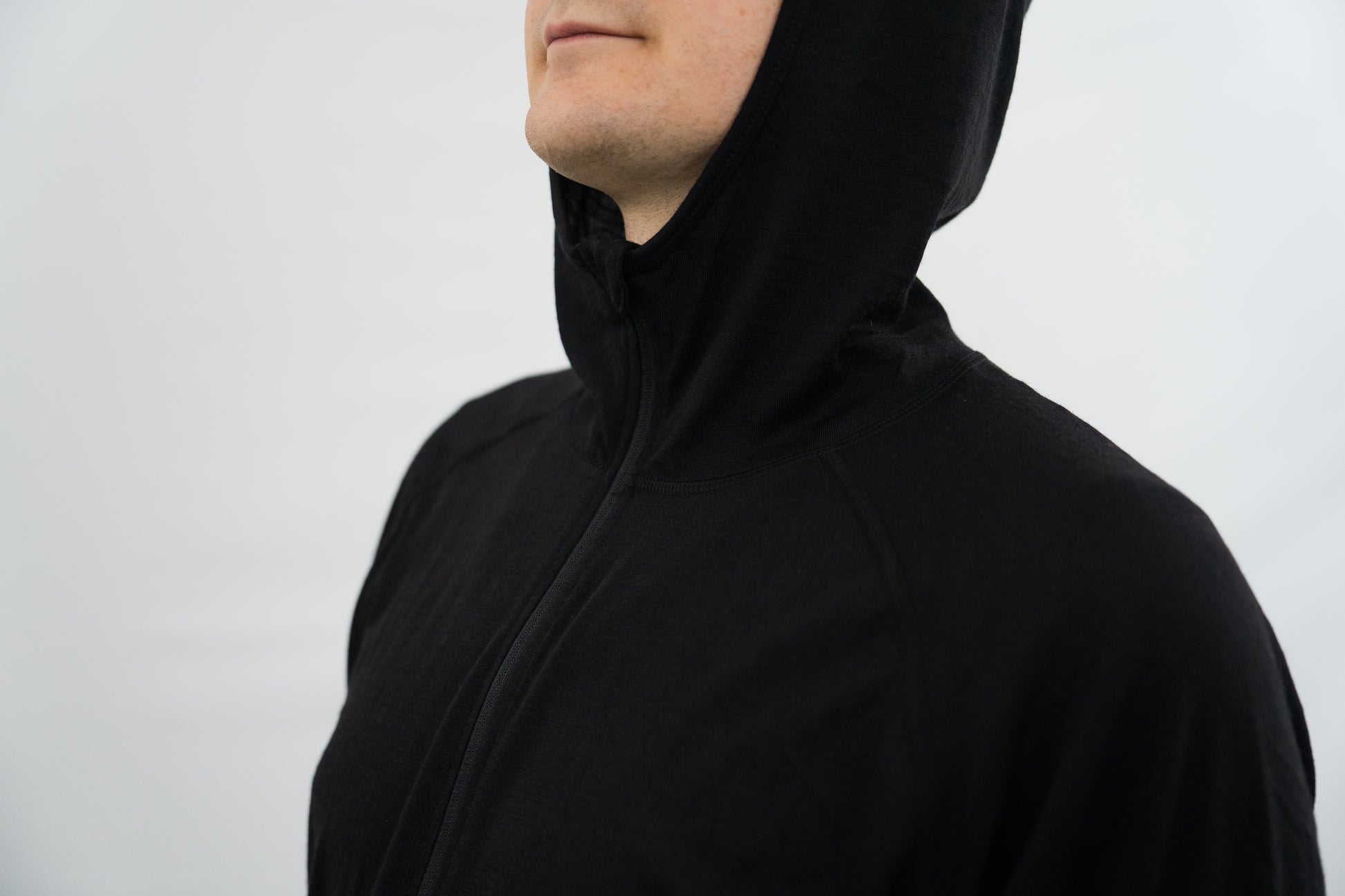 Top half of person wearing lack wool base layer hoodie with hood on from Squak Mountain Co.
